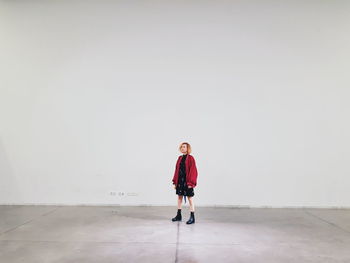 Full length portrait of woman standing against wall