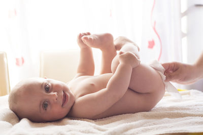 Portrait of shirtless baby lying on bed at home