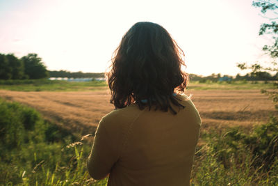 Rear view of woman standing on field against sky