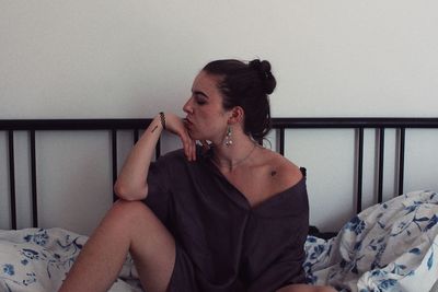 Young woman sitting on bed at home