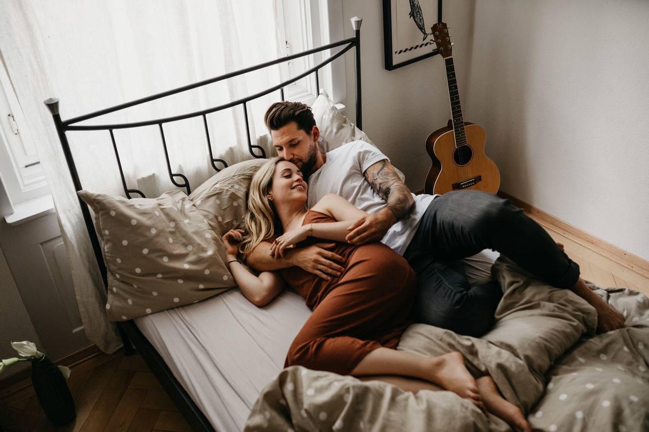 High angle view of young couple lying on bed at home