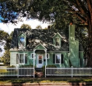 House and trees growing in yard against sky