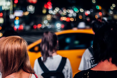 Rear view of people in illuminated city at night