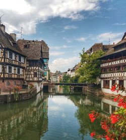 Bridge over river by buildings against sky