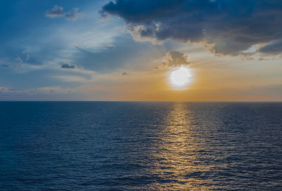 Scenic view of sea against cloudy sky during sunset