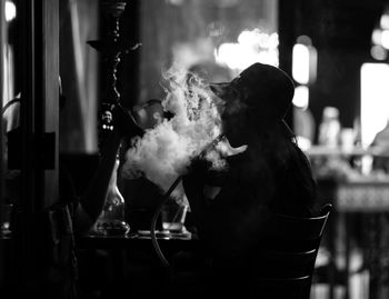 Silhouette woman smoking waterpipe in restaurant