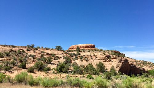 Rock formations on landscape against clear blue sky