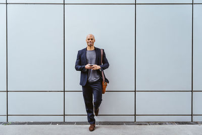 Portrait of young man standing against wall