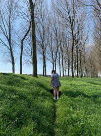 Rear view of woman walking on field