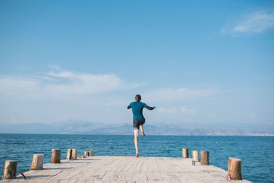 Rear view of man looking at sea against sky