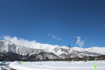 Scenic view of snow covered mountains against blue sky