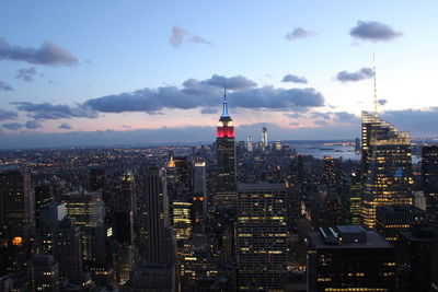 View of city lit up against cloudy sky