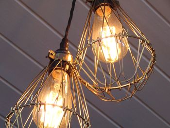 Low angle view of illuminated light bulbs hanging on ceiling