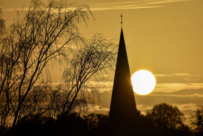 Low angle view of silhouette trees against orange sky