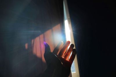 Close-up of human hand reaching towards sunlight