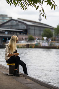 Rear view of woman sitting on bollard