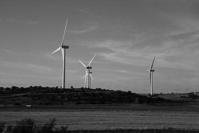 Windmills on field against sky