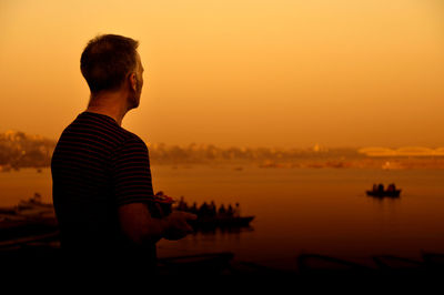 Silhouette man looking at sea against sky during sunset