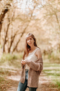 Portrait of a girl with brown hair, in a cardigan, on a walk in the forest.