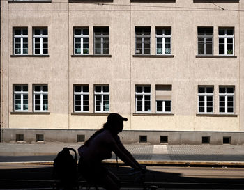 Side view of man sitting on bench against building