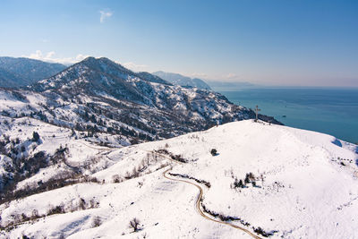 Scenic view of snowcapped mountains by sea against sky