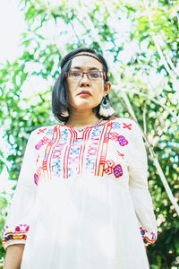 Portrait of young woman standing against plants