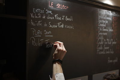 Cropped hand writing on blackboard