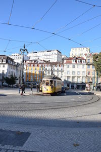 Cars on road by buildings against sky in city