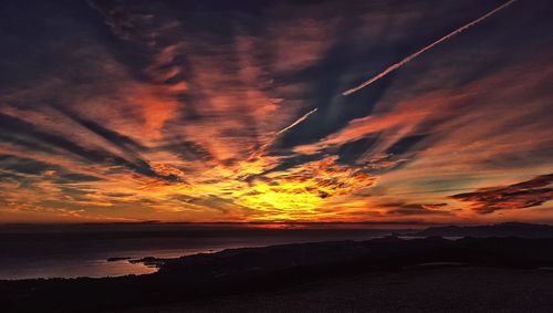 Scenic view of sea against dramatic sky during sunset