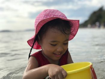 Girl holding bucket while sitting at beach