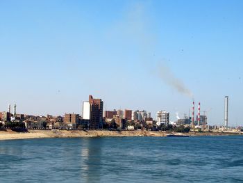 Sea by buildings against clear blue sky