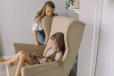 Siblings using digital tablet at home