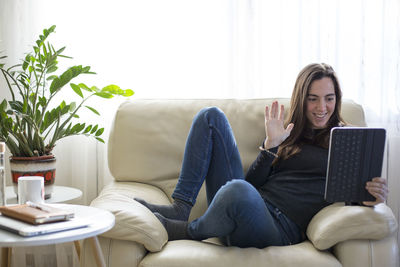 Young woman using phone while sitting on sofa at home