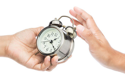 Cropped hands with alarm clock against white background
