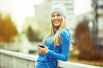 Portrait of smiling young woman using mobile phone outdoors