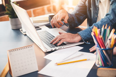 Midsection of man using laptop on table