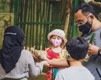 Little girl looking at the pigeon eating from the hands.