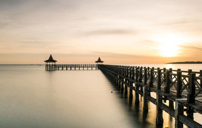 Pier over sea against sky during sunset