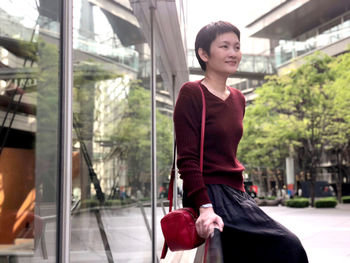 Portrait of smiling woman standing by glass