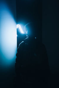 Silhouette person holding illuminated lights at night