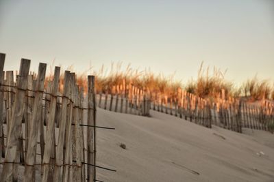 Wooden fence on field against sky during sunset