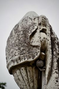 Low angle view of old statue against sky