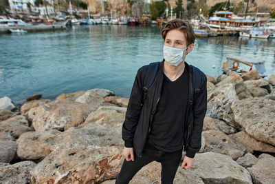 Portrait of man standing on rock wearing protective face mask