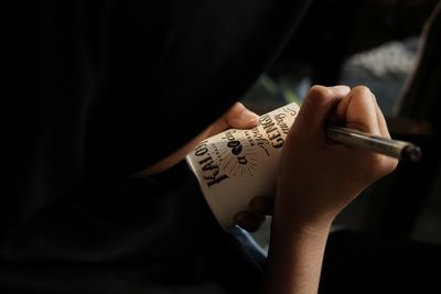 Cropped hand writing on disposable cup