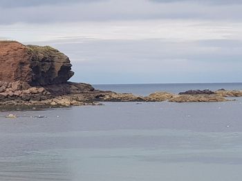 Rock formation in sea against sky