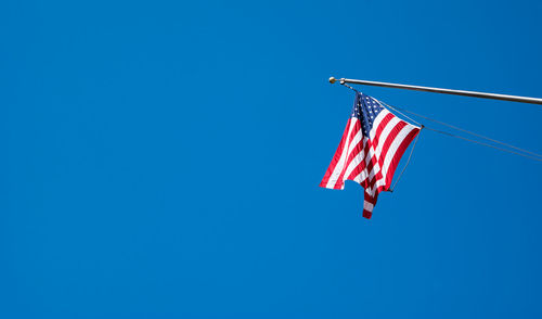 Low angle view of american flag against clear blue sky