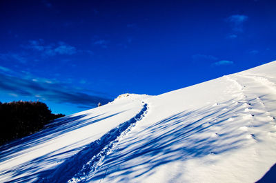 Low angle view of snow covered mountain against blue sky