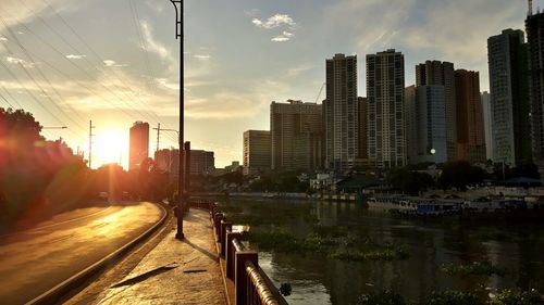 River amidst buildings in city against sky during sunset