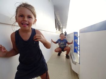 Portrait of happy siblings standing in boat against clear sky