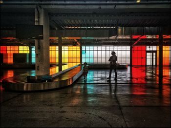 Rear view of man standing in illuminated subway station